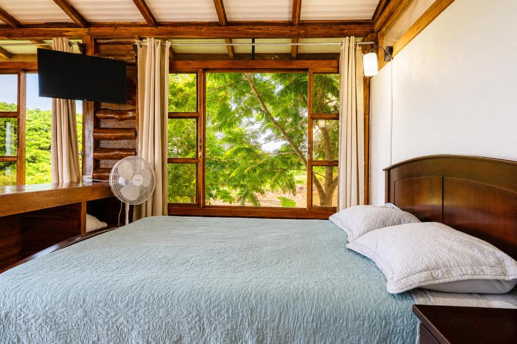 a bedroom with a bed and a large window at Cabañas Bella Vista in Hojancha