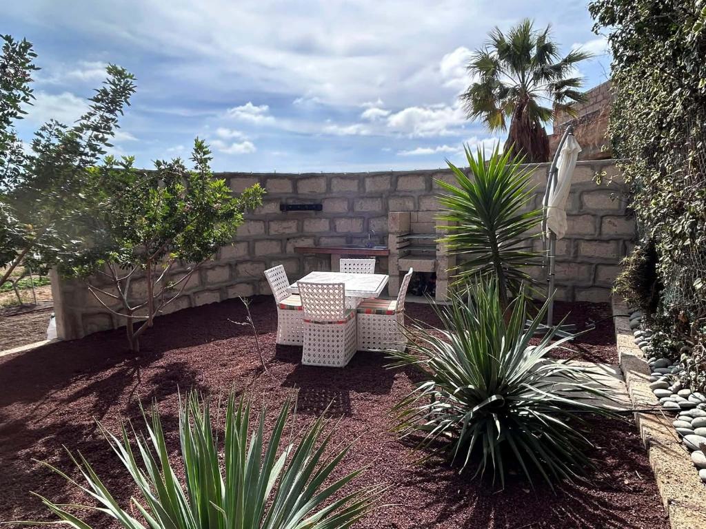 a patio with a table and chairs in a garden at Cuevita El Abrigo - 1 dormitorio in Lomo de Arico