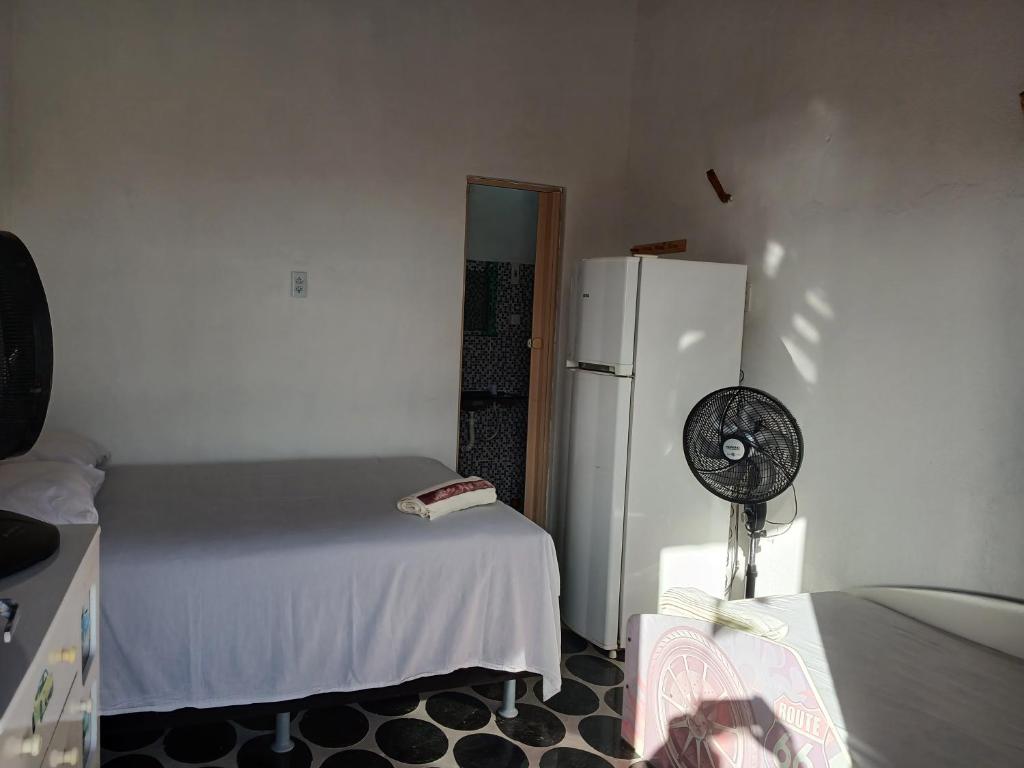 a kitchen with a white refrigerator and a bed at Pousada Praiamar in Beberibe