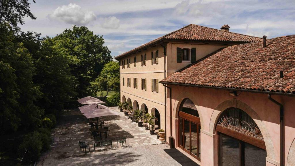 a building with tables and umbrellas in front of it at Agriturismo Rechsteiner in Ponte di Piave