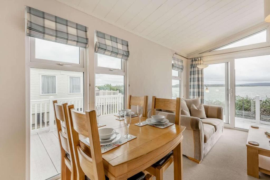 a dining room with a table and chairs and windows at Bay View 2-Bed Lodge with Glorious Harbour View and Balcony in Poole