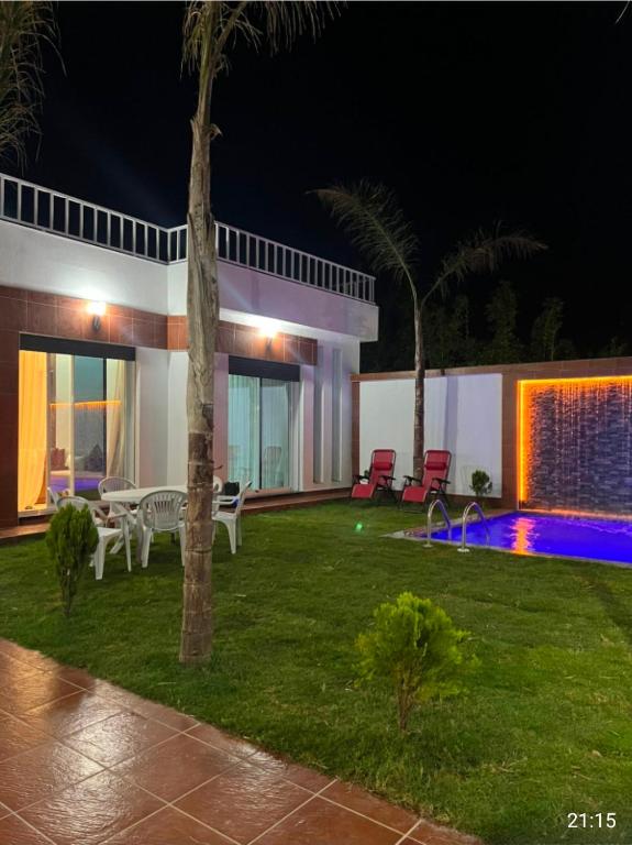 a backyard at night with a swimming pool at villa la perle in Asilah
