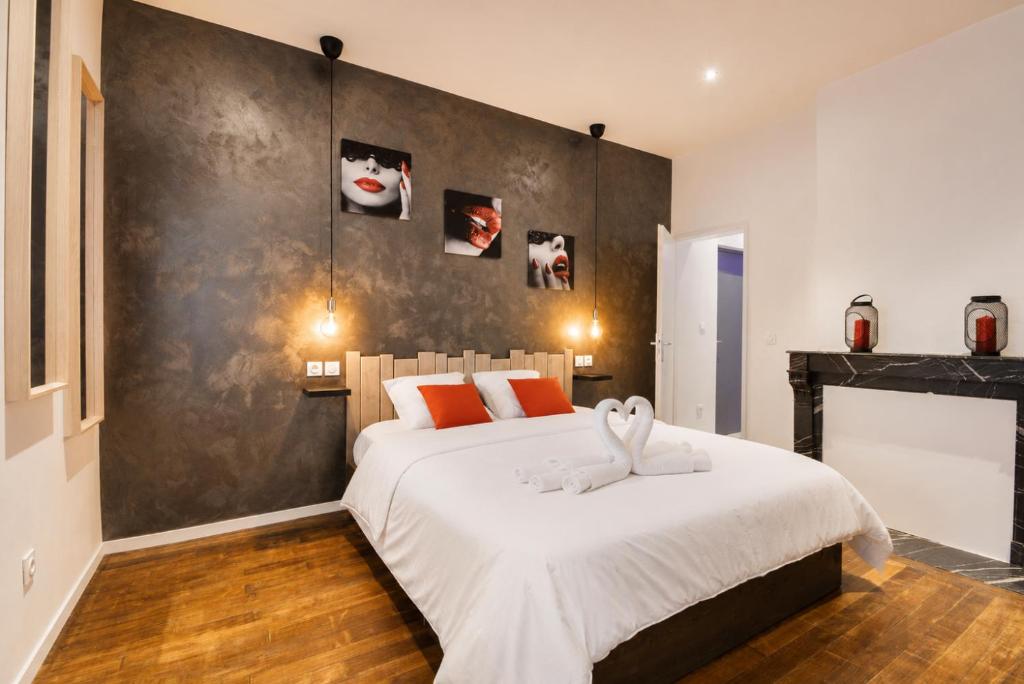 a bedroom with a large white bed and a fireplace at Sous le Charme de Charles Sauna & Jacuzzi Nancy in Nancy