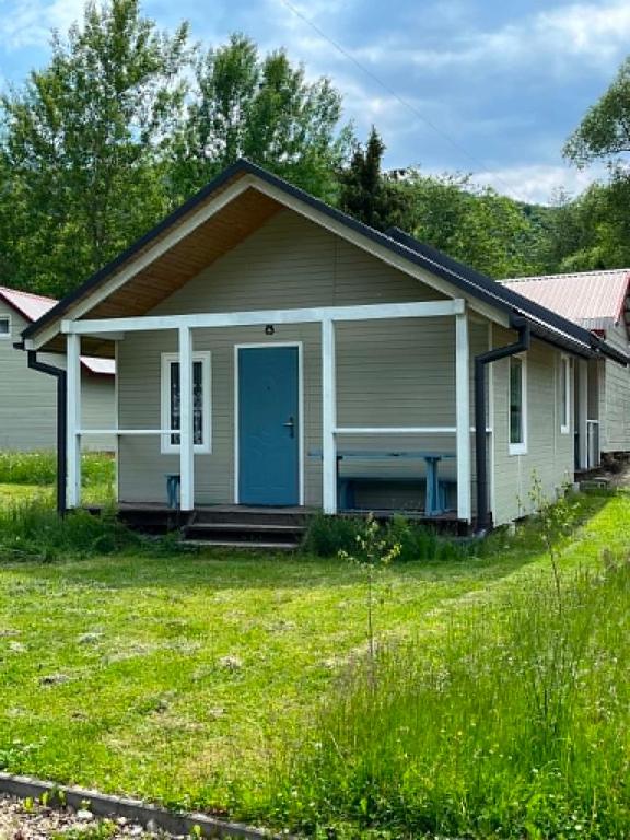 a small house with a blue door in a yard at BiesChatki in Wetlina