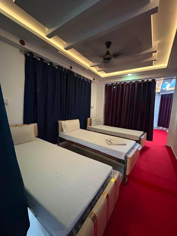 three beds in a room with a red carpet at Hotel Diamond Palace, Madiwala in Bangalore