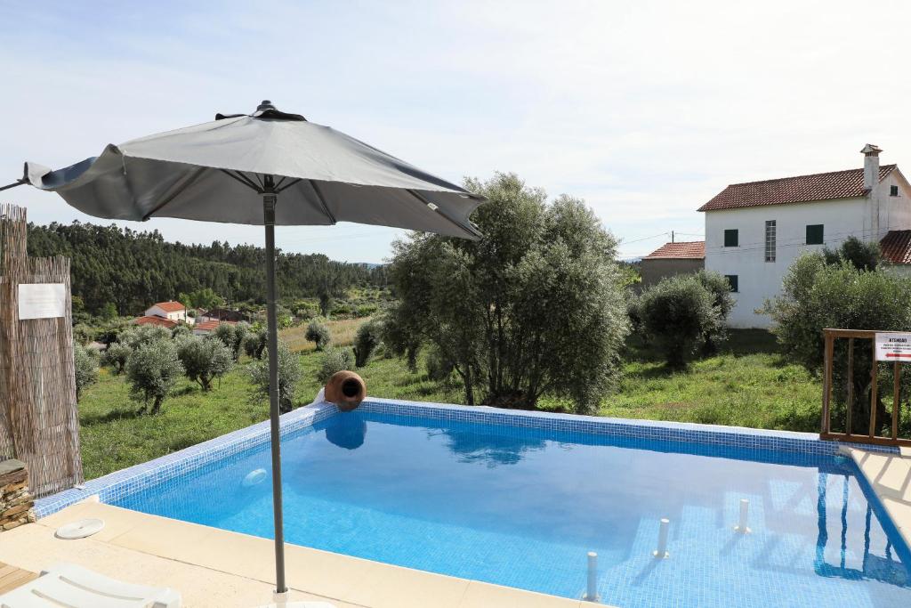 an umbrella sitting next to a swimming pool at Casa da Moleira in Chaveirinha