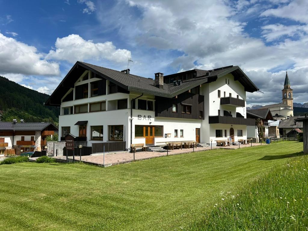 ein großes weißes Haus mit einem grünen Feld in der Unterkunft Hotel D'La Varda in Padola