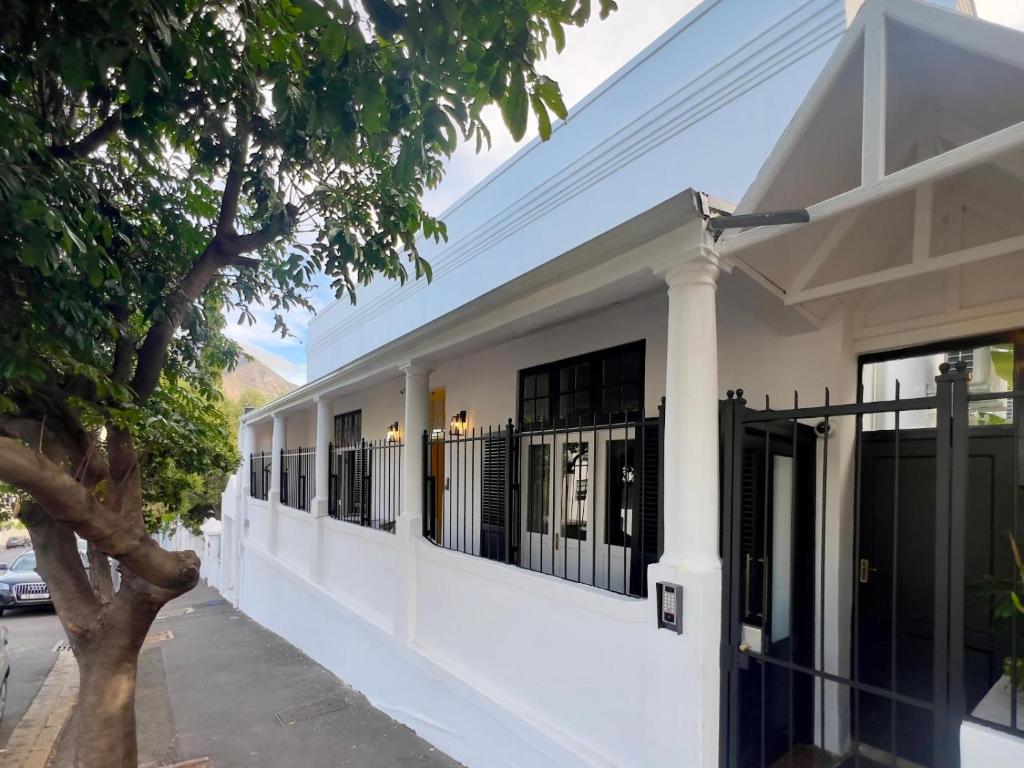 a white building with a fence on a street at Nomad City Suites in Cape Town