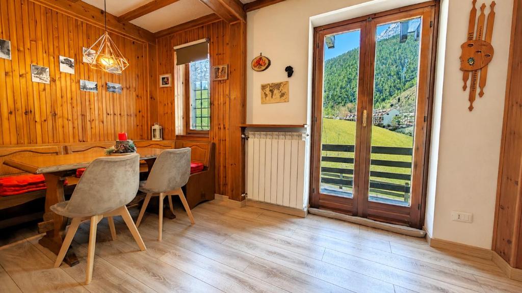 a dining room with a table and chairs and a window at Hostdomus - Seguret in Cesana Torinese