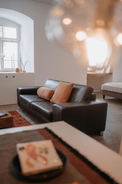 a living room with a black leather couch and a table at Historische, moderne Stadtwohnung in Riedlingen