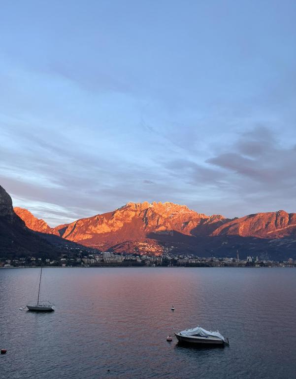 two boats in a large body of water with mountains at COZY LAKE COMO APARTMENTS in Valmadrera