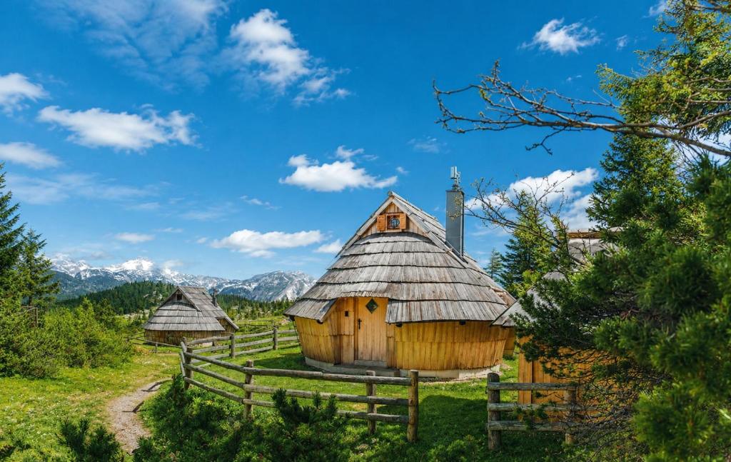 a wooden hut in a field with a fence at Chalet Lepenatka with Sauna - I feel Alps in Stahovica