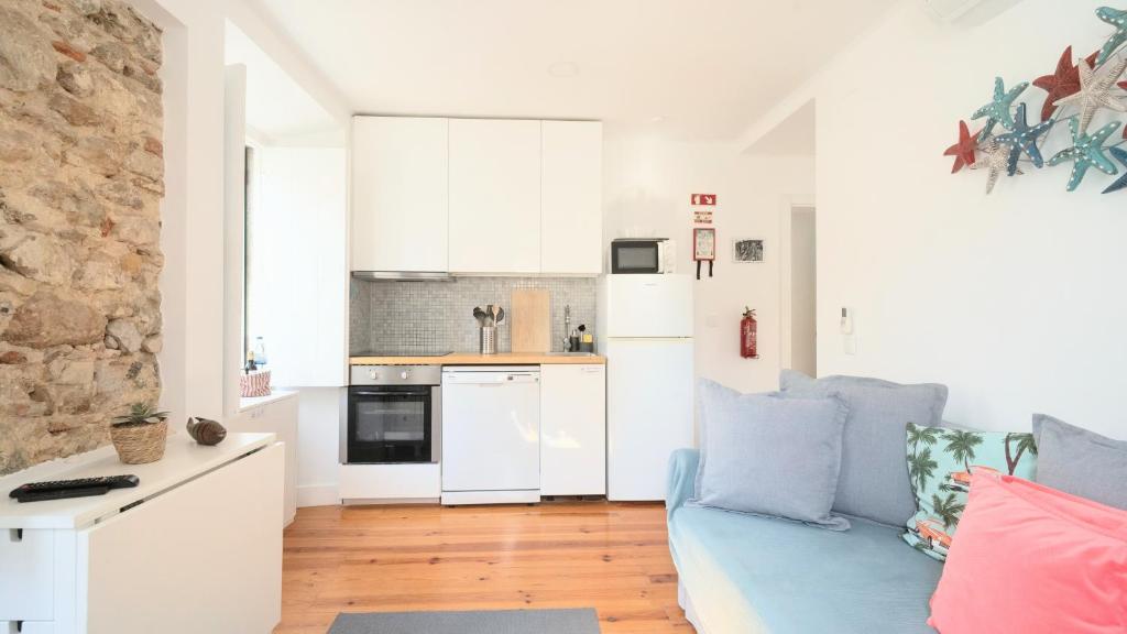 a living room with a blue couch and a kitchen at Apartamentos Aurea - Sesimbra in Sesimbra