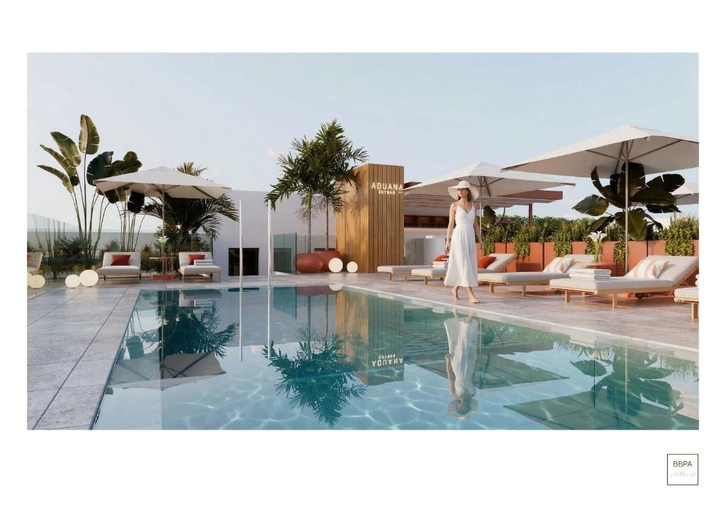 a woman is walking by a swimming pool at Aduana Suites in Salou