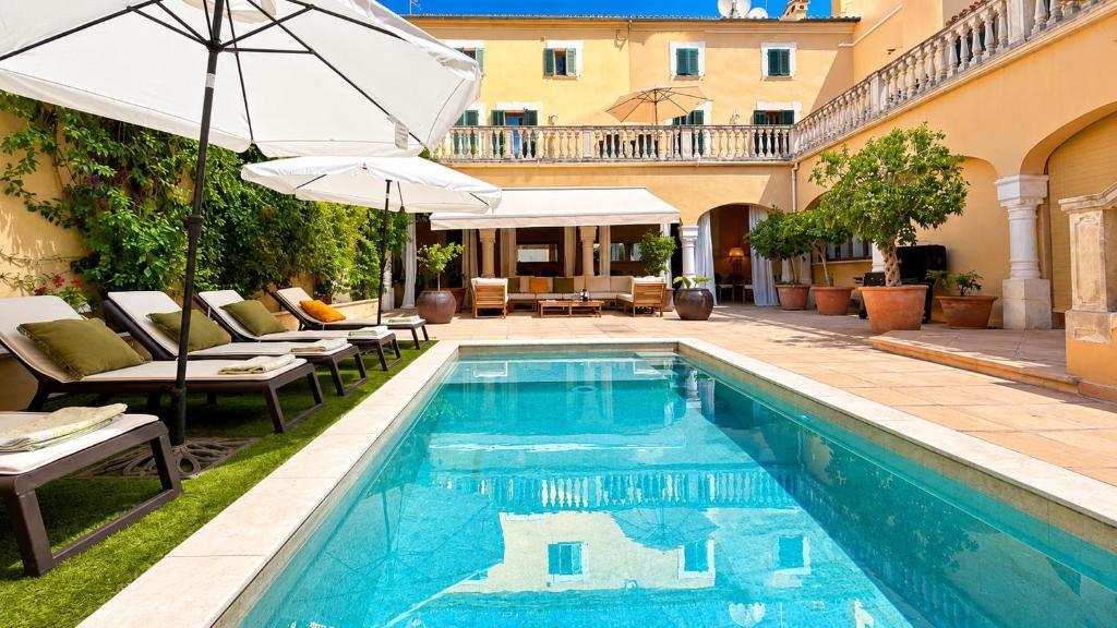 a pool with chairs and an umbrella next to a building at Villa Nekazabal in Sa Pobla