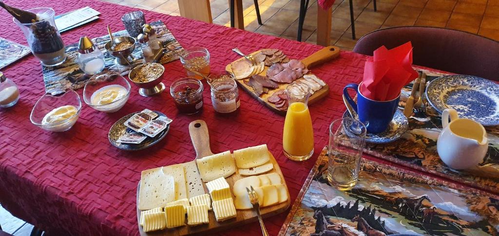 a red table with cheese and other food on it at Pension Malu die hundefreundliche Pension mit Frühstück ab 6 Uhr in Todenbüttel