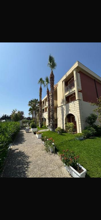 a building with palm trees next to a sidewalk at Casa Vacanze Oasi Felicita in Nova Siri Marina