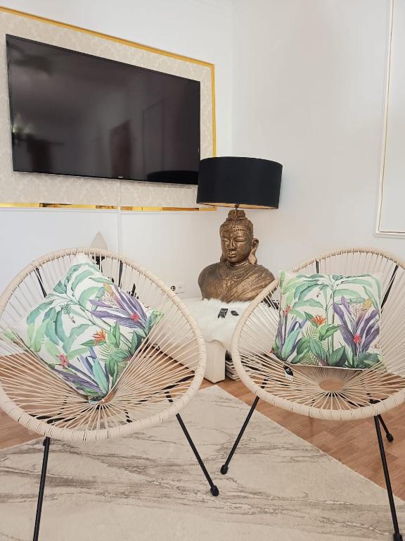 a living room with two chairs and a table with a bust at Marujo Home & Heart in Penedo Gordo