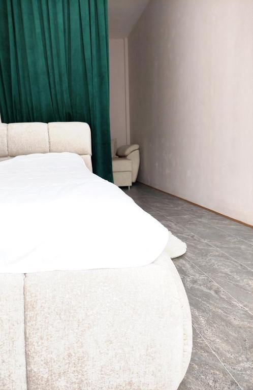 a white bed in a room with a green curtain at Ap Blessedplace Rîșcani-New Bldg in Chişinău