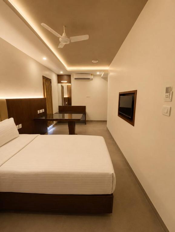 a hotel room with a bed and a table at Arthana Grand Inn in Udumalaippettai
