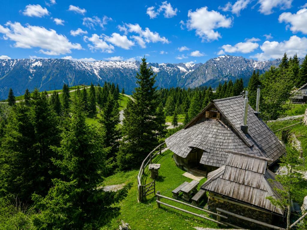 a house on a hill with mountains in the background at Alpine Chalet Velika Planina - Irenca - I Feel Alps in Stahovica