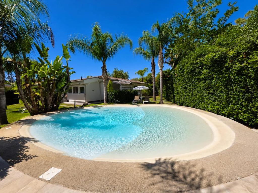a large swimming pool in a yard with trees at Villa Lucy Eco Friendly in Fontane Bianche