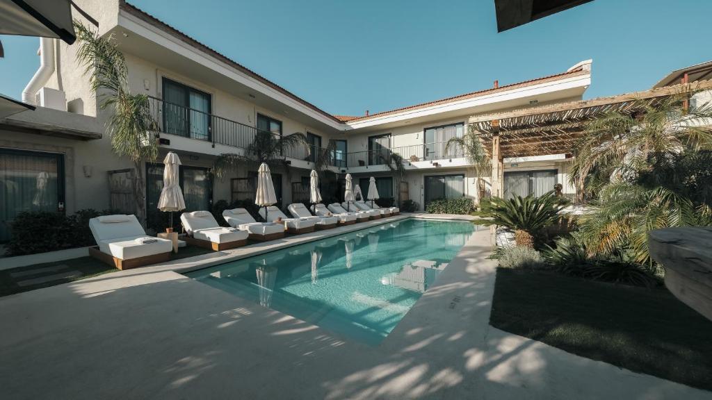 a swimming pool with chairs and umbrellas next to a building at Wakana Alaçatı in Alaçatı