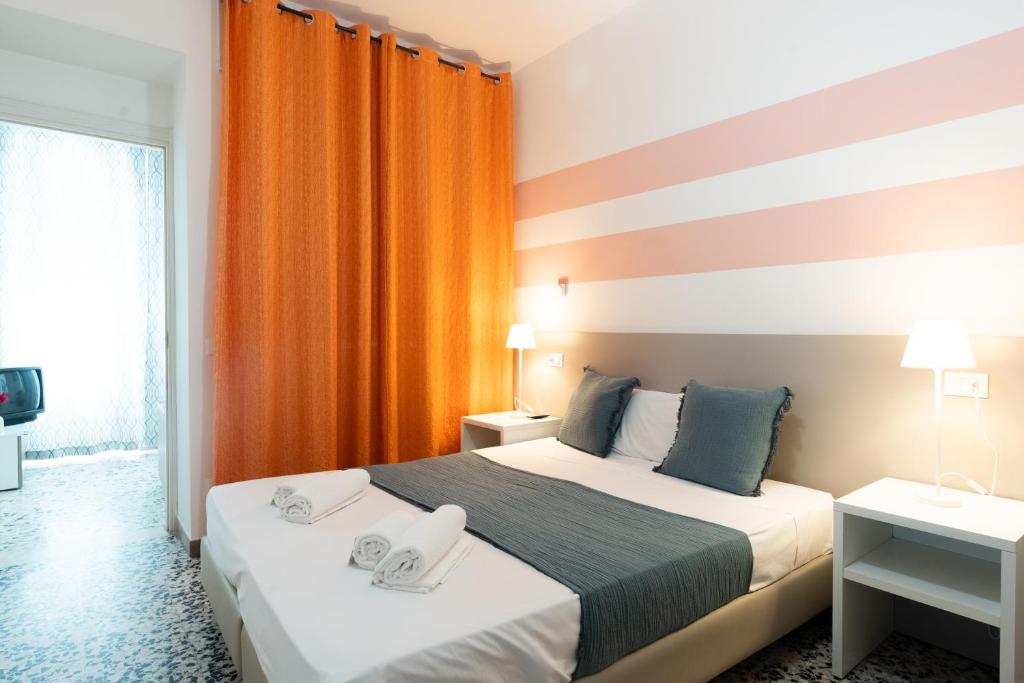 a hotel room with two beds and an orange curtain at B&B K Beach Lake Endine in Endine Gaiano