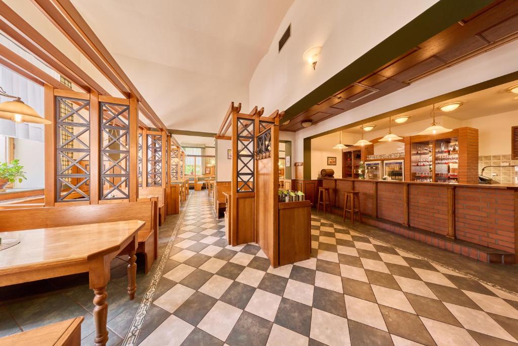 a restaurant with wooden tables and a checkered floor at Hotel Krakonoš in Trutnov
