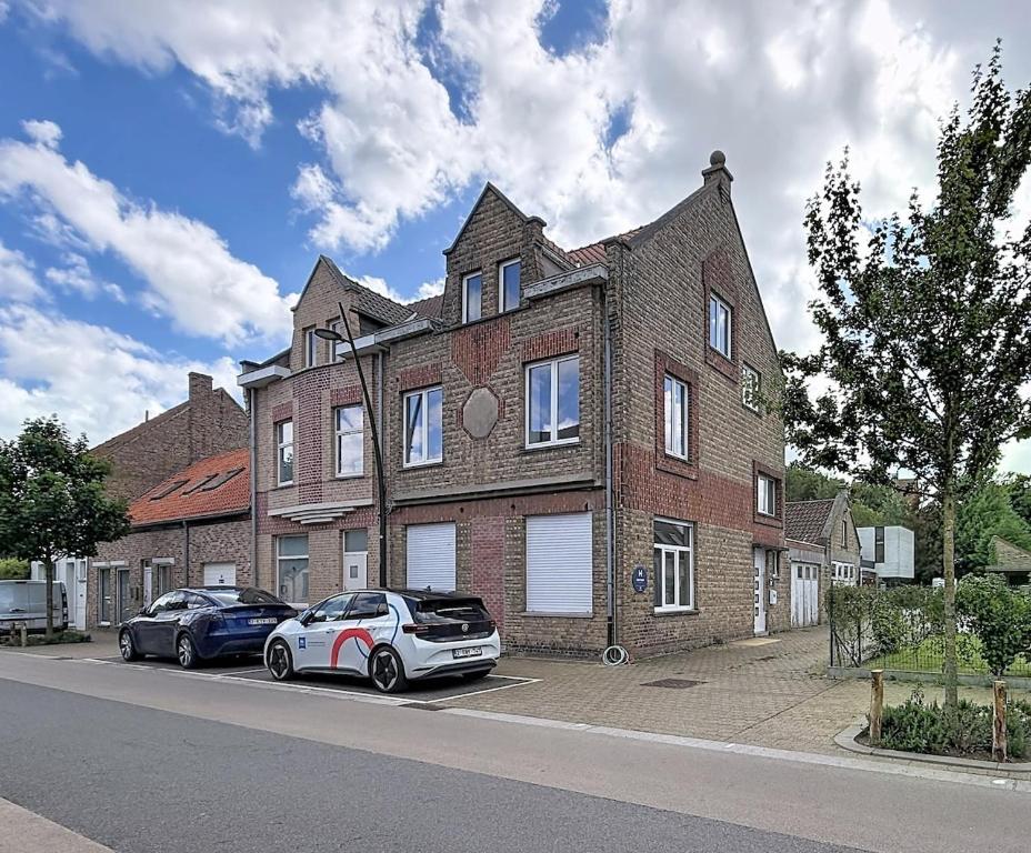 a large brick house with two cars parked in front of it at Stellaross - Koksijde in Koksijde