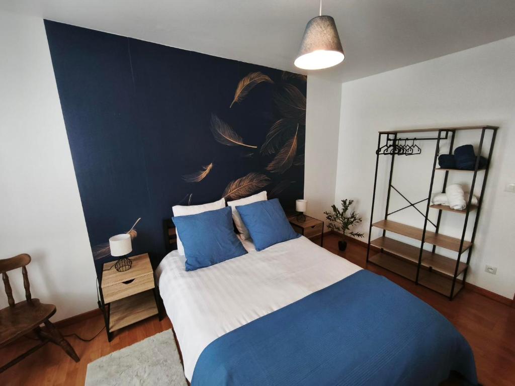 a bedroom with a blue and white bed with a large wall at Berges de la Suippe in Warmeriville