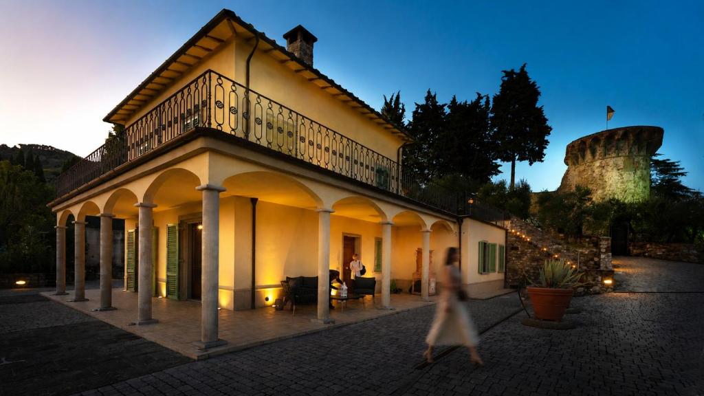 a woman walking past a building with a tower in the background at Panoramic villa near Florence in Pescia