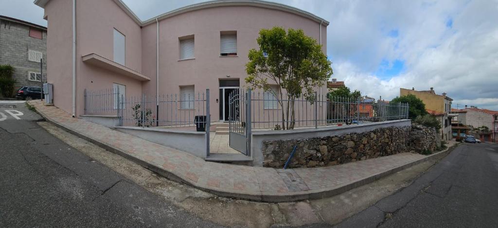 a house with a stone retaining wall and a fence at B&B Le Fontane in Bono