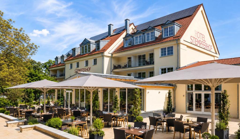 a restaurant with tables and umbrellas in front of a building at Hotel Stempferhof in Gößweinstein