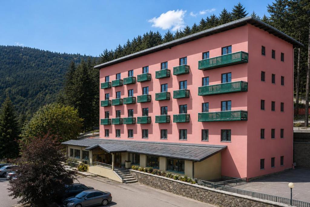 a pink building with cars parked in a parking lot at Residenza Lorica in Lorica