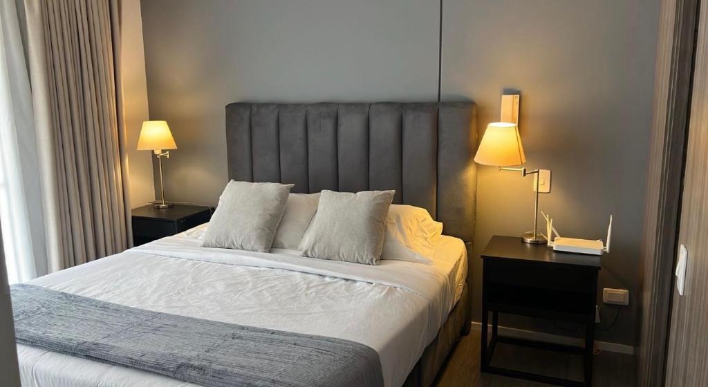 a bedroom with a large bed with two night stands and two lamps at Distrito prime 1-303 in Bogotá