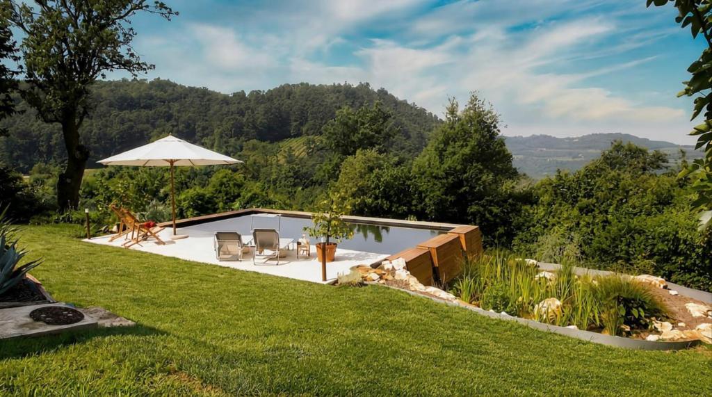 a backyard with a pool and an umbrella at Casa in Bioedilizia con Bio Piscina Naturale – Ai Due Gelsi in Grancona