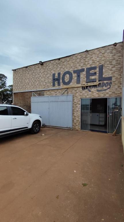 a white car parked in front of a hotel at Hotel Gramados in Porangatu