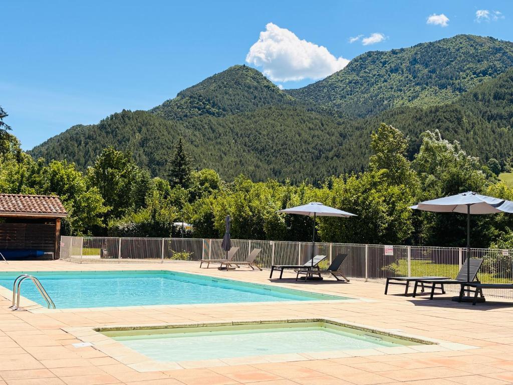 a swimming pool with mountains in the background at Le Vercors Park in Die