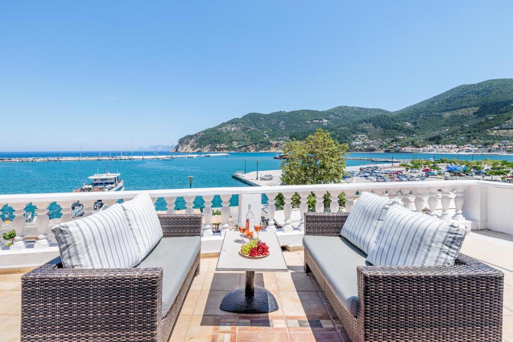 a balcony with chairs and a table with a view of the ocean at Adonis Rooms in Skopelos Town
