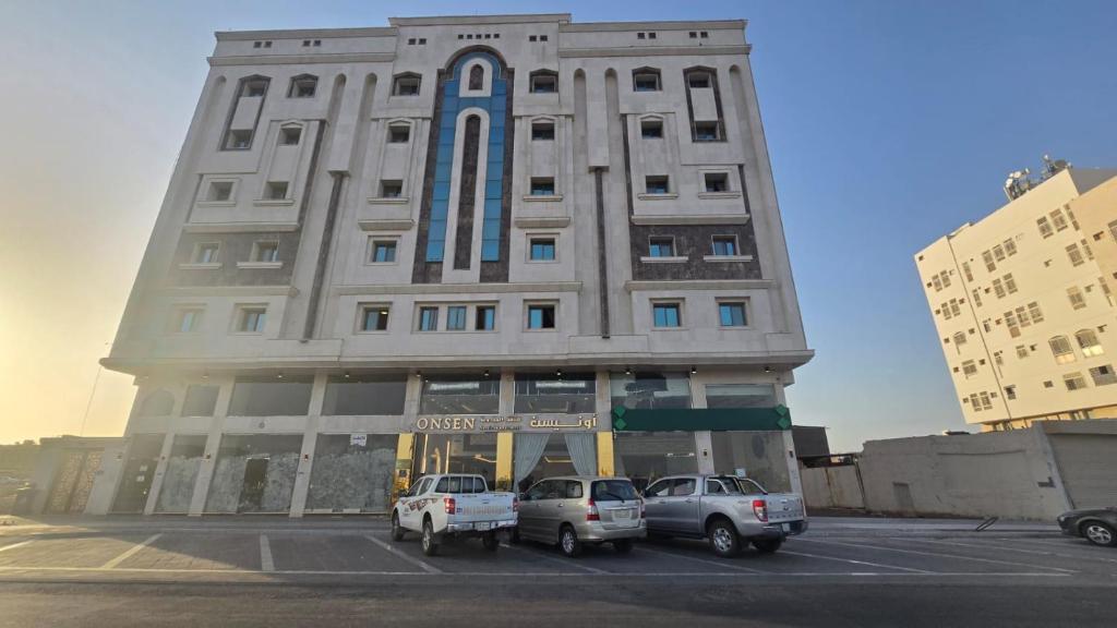 a tall building with cars parked in a parking lot at شقق أون يسن للشقق المخدومة in Medina