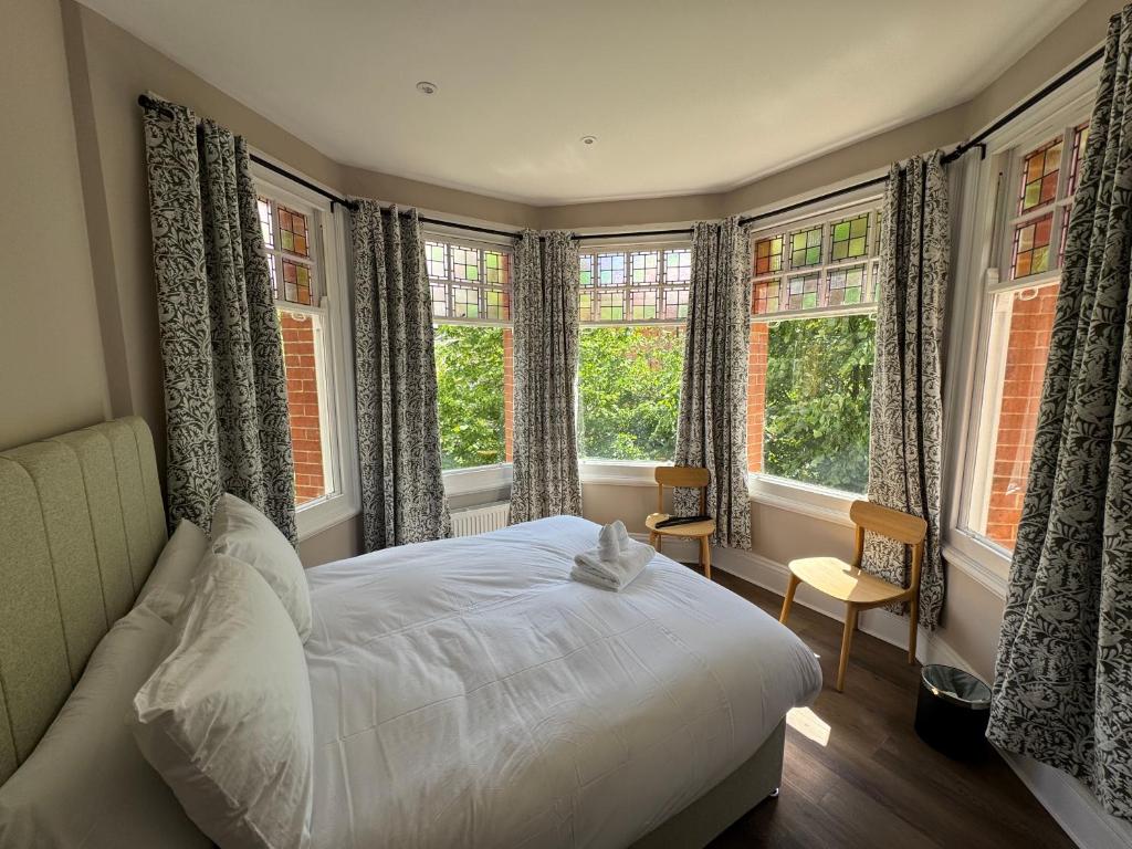 a bedroom with a white bed and windows at Charlie Hotel in London