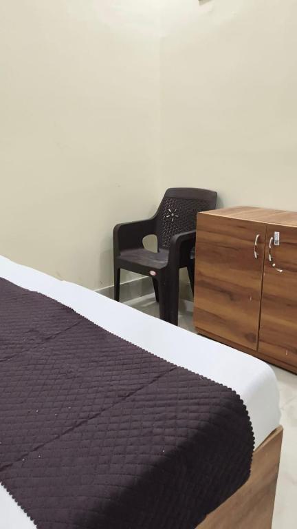 a bedroom with a bed and a chair and a dresser at Hotel Kanhaiya Inn in Haridwār
