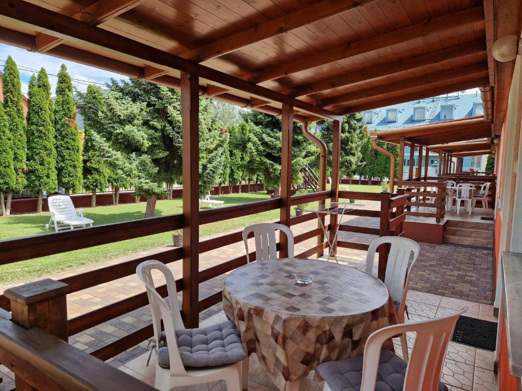 a wooden porch with a table and chairs on it at Boglárka Apartmanház in Mezőkövesd