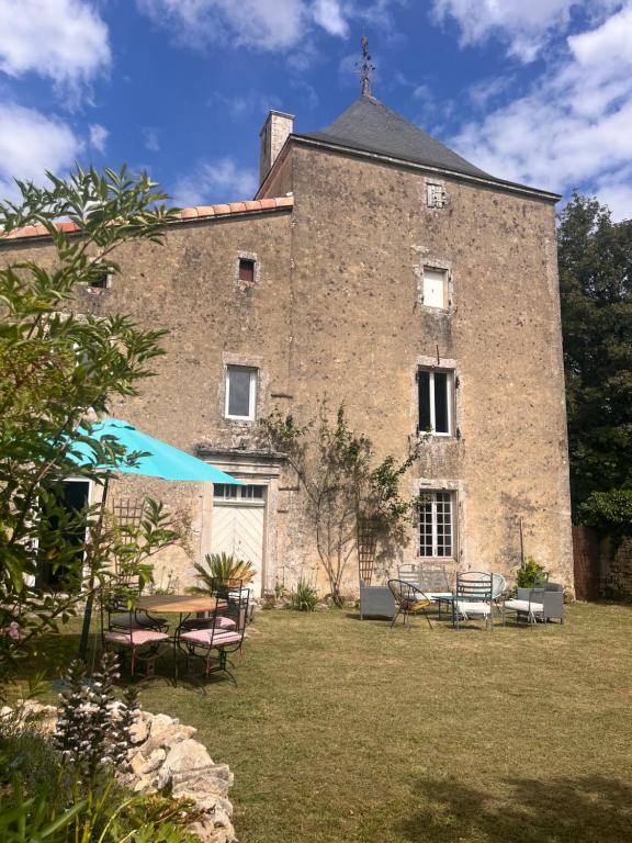 a large brick building with a table and chairs at Le pavillon des sœurs in Fontenille