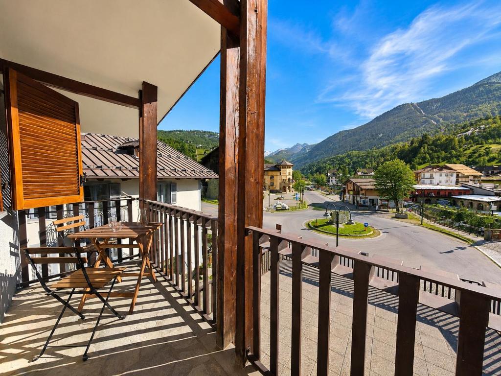 a wooden balcony with a table and a view of a street at Hostdomus - Casa Ariel in Cesana Torinese