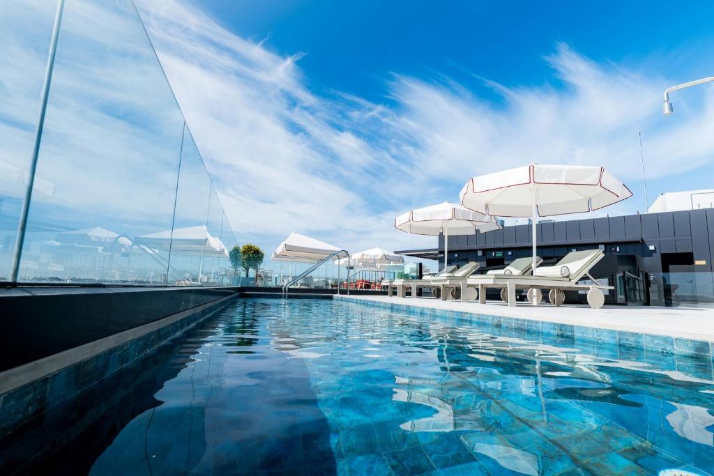 a swimming pool with chairs and an umbrella and a building at Sercotel Sevilla Don Luciano in Seville