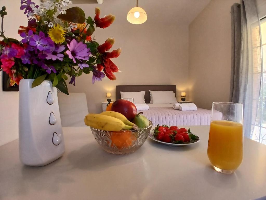 a table with a bowl of fruit and a vase of flowers at Sandra's Nest Gaios Paxos in Gaios