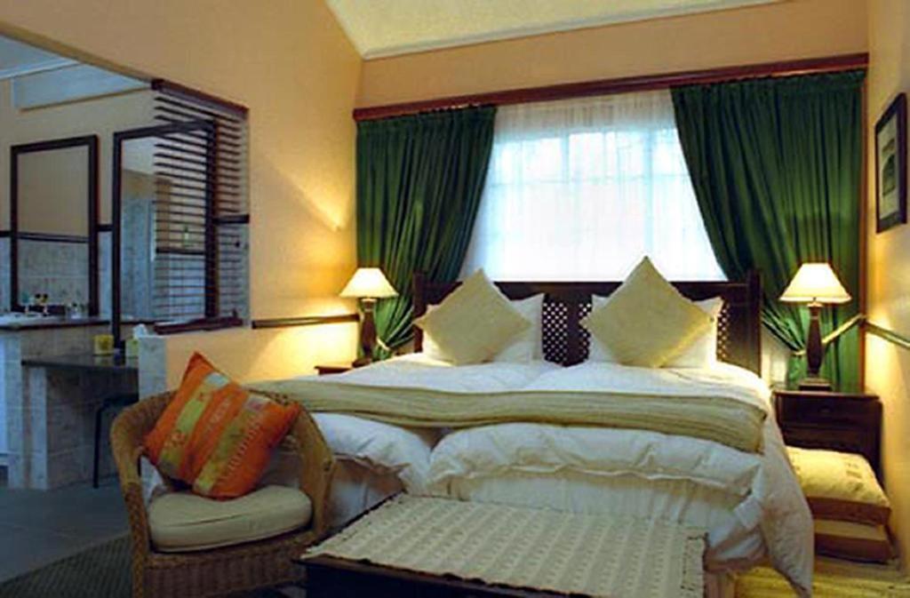 a bedroom with a large bed with green curtains at Great Dane at Brittlewood in Underberg