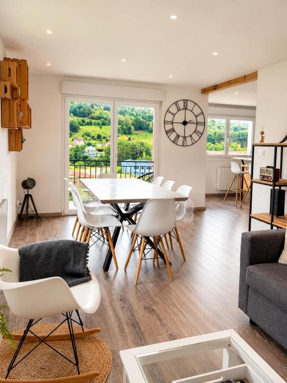 a living room with a table and chairs and a clock at Appart Vosges in Fresse-sur-Moselle